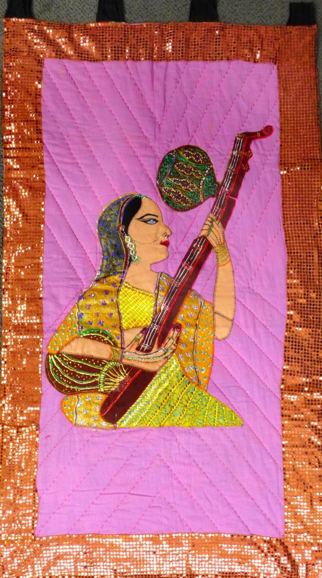a sitting Bengali lady playing a tanpura. 